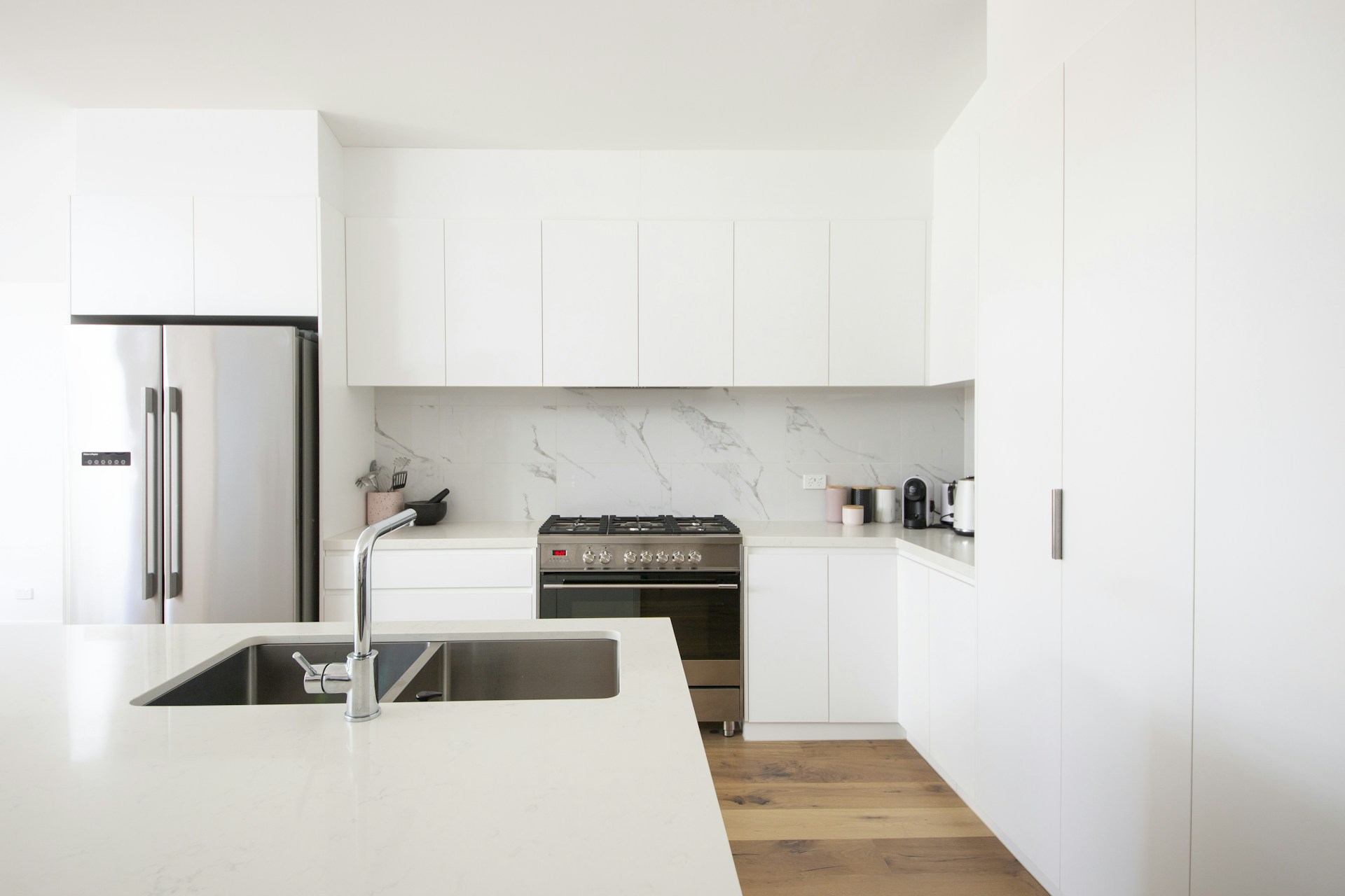 Minimalist modular kitchen with clean white flat-panel cabinets and hidden handles