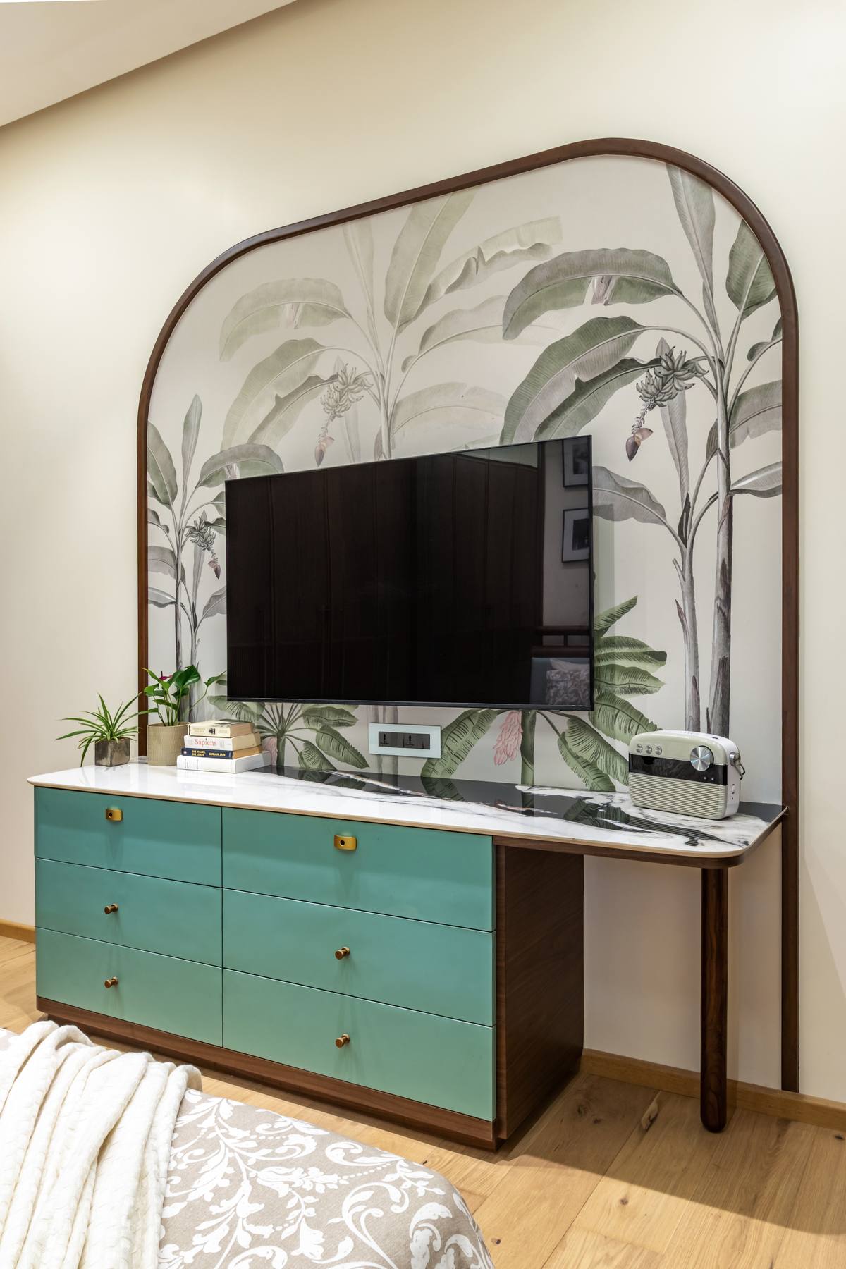 Bedroom TV unit with botanical wallpaper and teal cabinetry by Beyond Briks