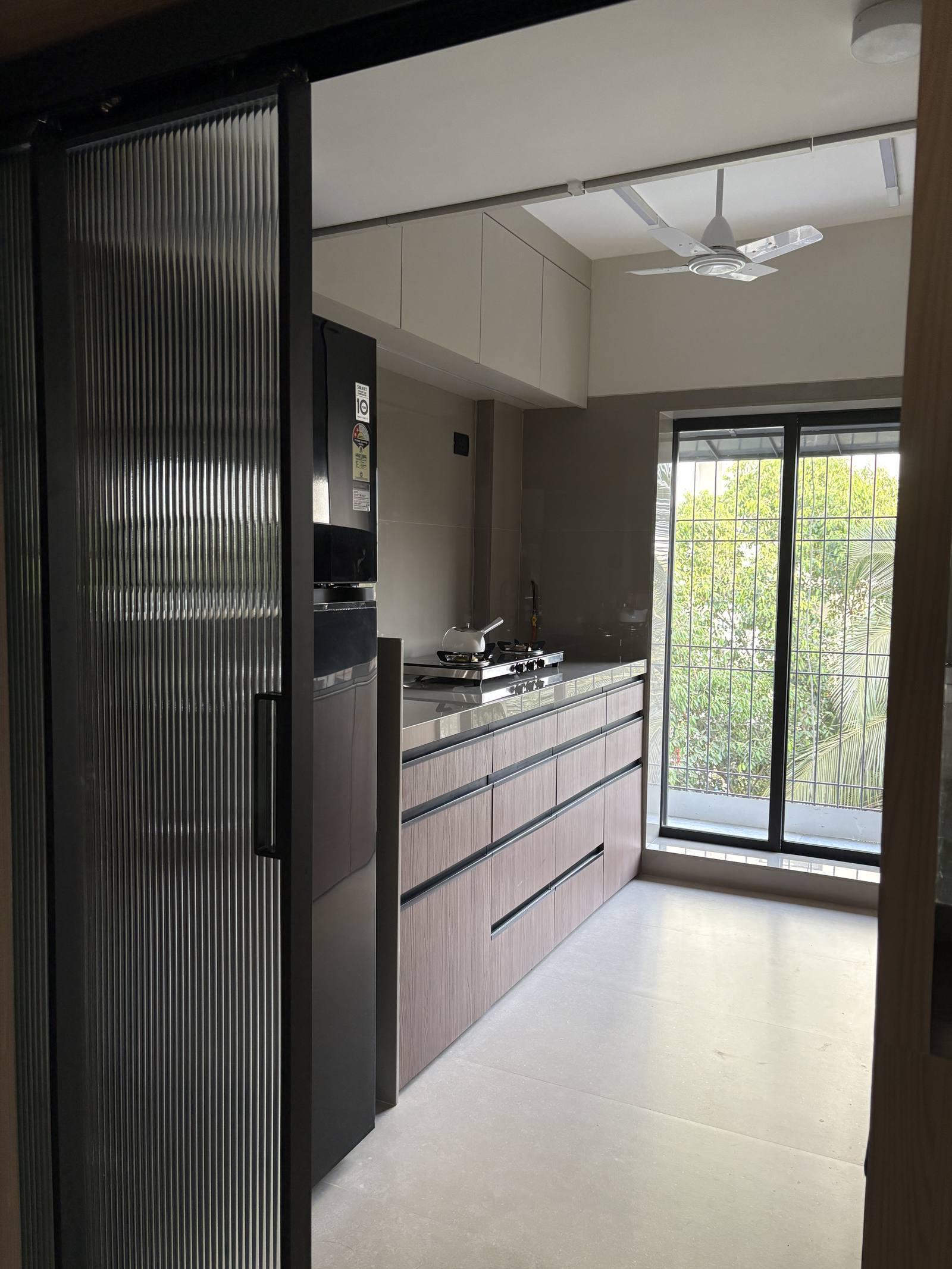Modular kitchen entrance with fluted glass sliding door by Beyond Briks