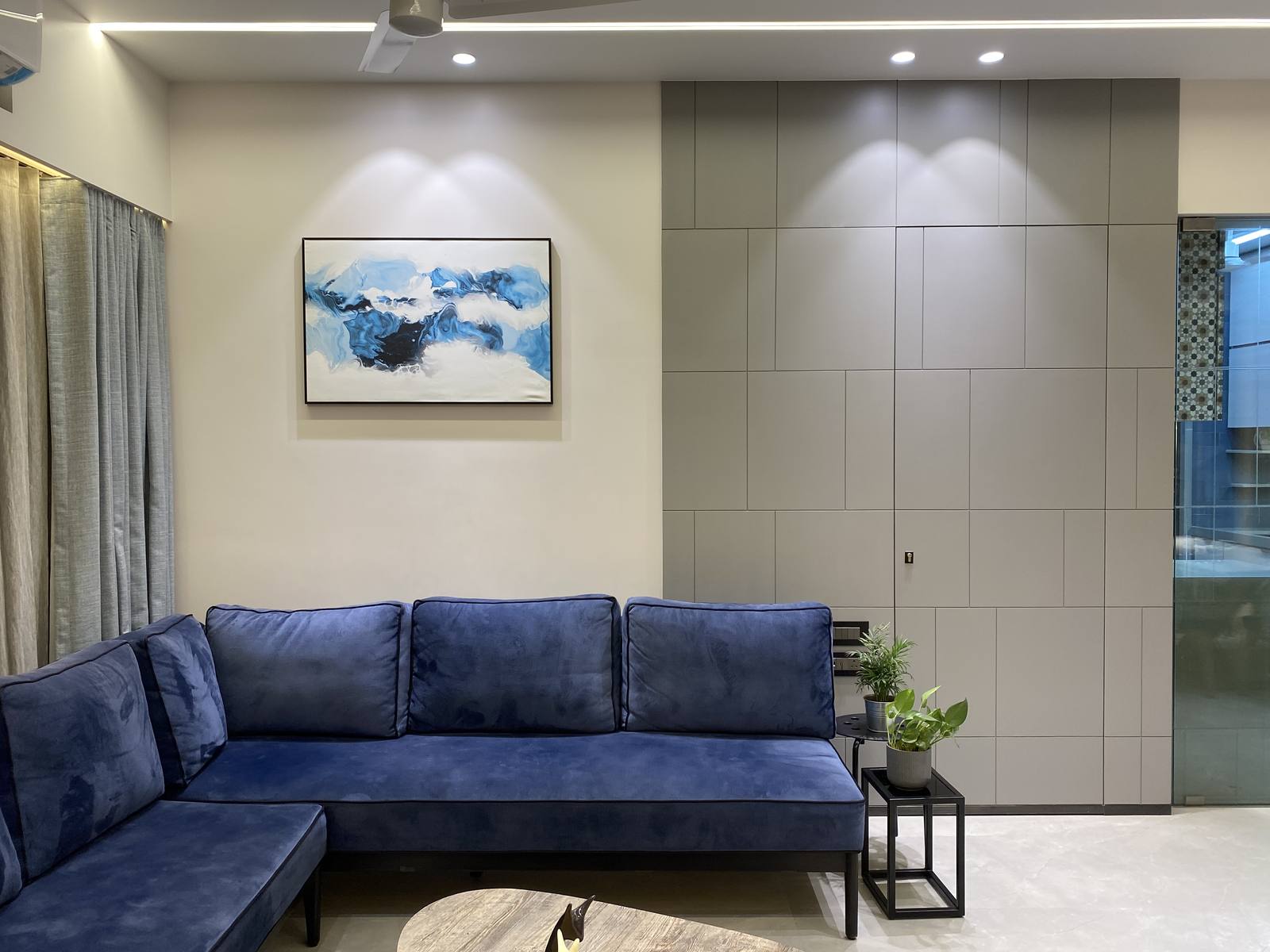 Living room with navy velvet sectional sofa and abstract art by Beyond Briks
